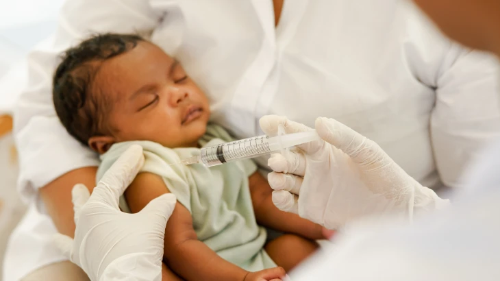 Bebê no colo tomando vacina