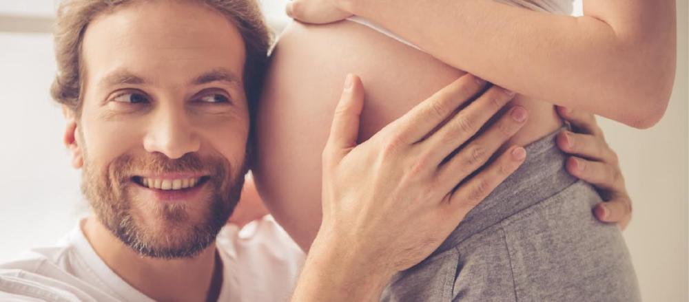 Gestante e seu parceiro abraçando sua barriga