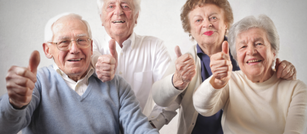 Quatro idosos fazendo sinal de positivo com o dedo polegar