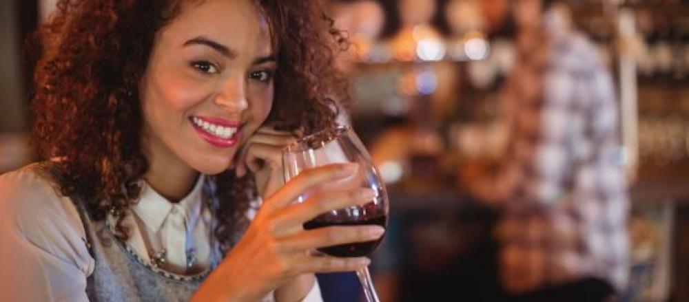 Mulher sorridente com uma taça de vinho na mão