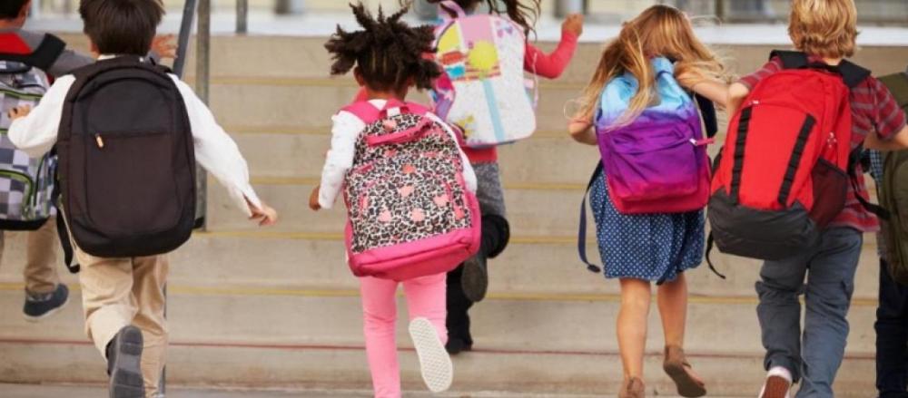 Crianças correndo enquanto carregam mochilas nas costas