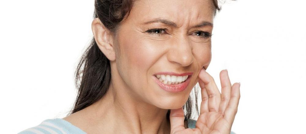 Mulher com a mão no rosto sentindo dores de dente