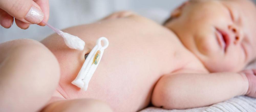 Mulher higienizando umbigo de recém-nascido