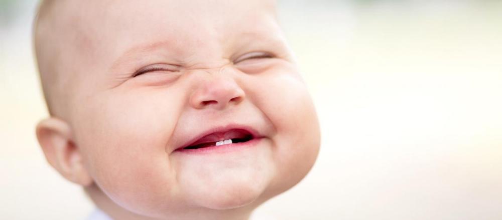Bebê sorrindo e mostrando um único dente na boca