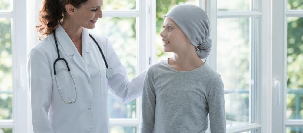 Médica ao lado de paciente em tratamento de câncer