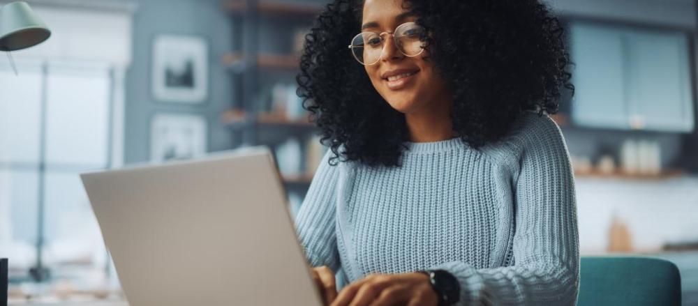 Mulher trabalhando sorridente, em frente a um computador