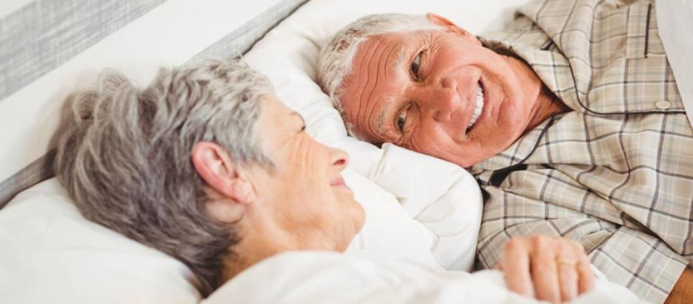 Casal de idosos sorrindo em uma cama