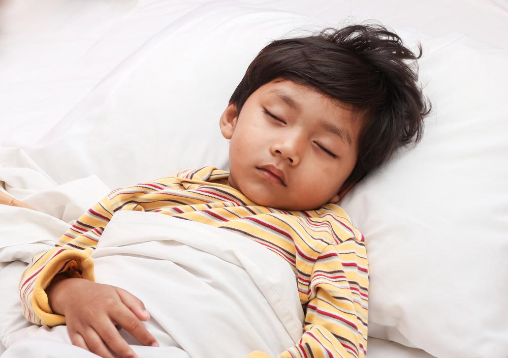 Criança dormindo profundamente na cama, ilustrando avaliação da qualidade do sono infantil, sinais de apneia, bruxismo e distúrbios de sono na infância.