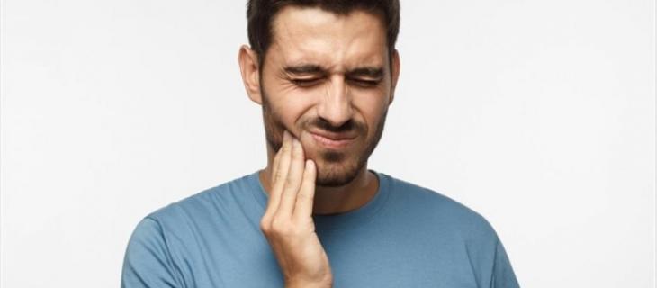 Imagem de um homem com a mão na bochecha e uma feição de dor