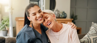 Profissional de saúde abraçando paciente idosa, representando o compromisso da Hapvida com qualidade, acolhimento e cuidado humanizado